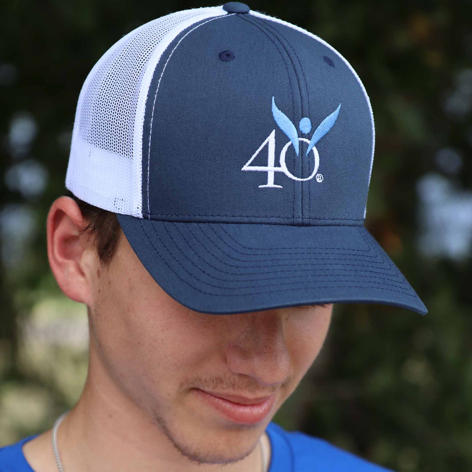 Person wearing a blue and white cap with a 40 Days for Life logo, outdoors.