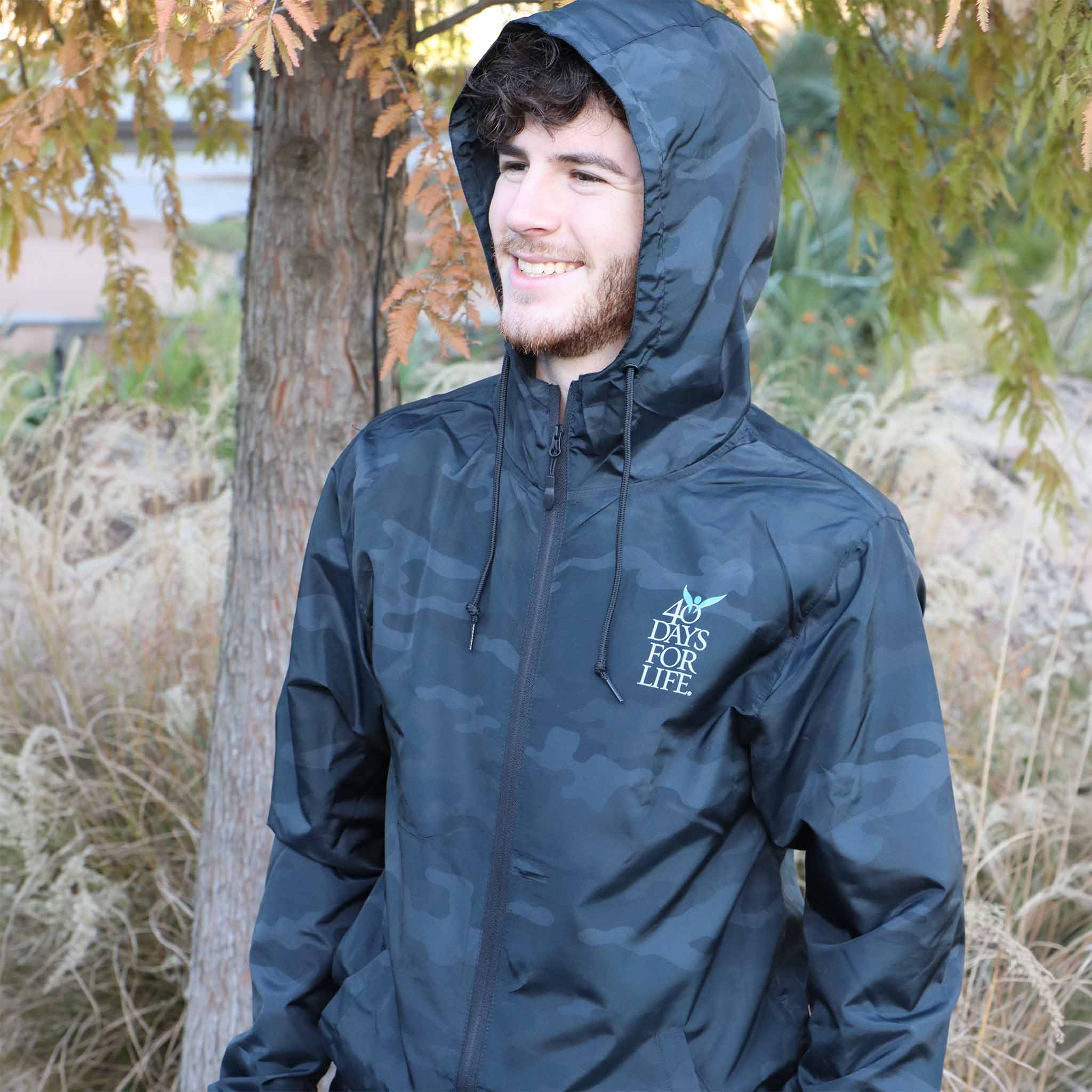Man wearing a black windbreaker with a 40 Days for Life logo outdoors